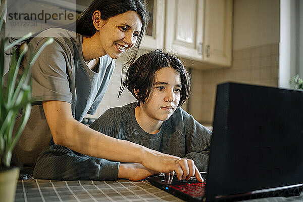 Glückliche Mutter und Sohn  die zu Hause Laptop benutzen