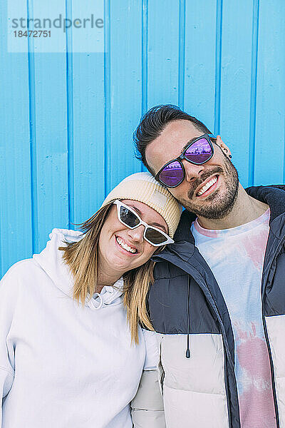 Lächelnder Freund und Freundin mit Sonnenbrille vor der Wand