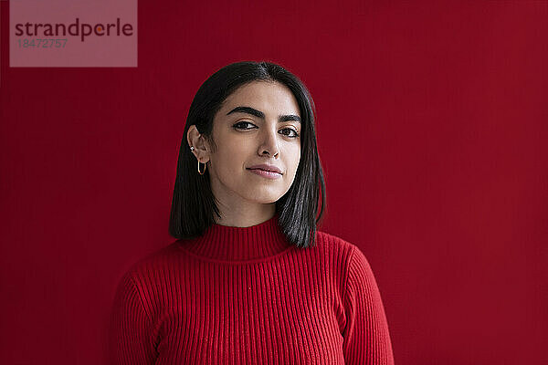 Selbstbewusste junge Frau vor rotem Hintergrund