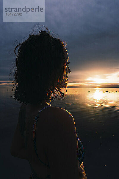 Junge Frau blickt auf den Sonnenuntergang