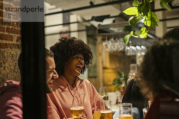 Glückliche Frau mit Afro-Frisur genießt im Restaurant