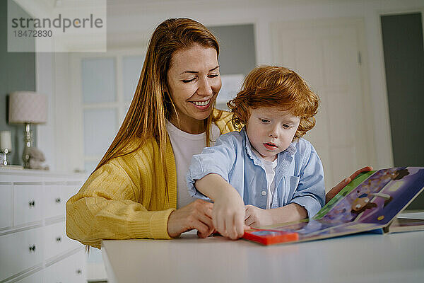 Glückliche Frau und Sohn lesen zu Hause Buch