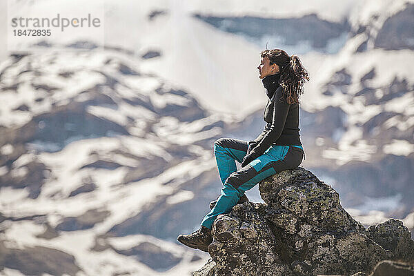 Wanderer sitzt an einem sonnigen Tag auf einem Felsen