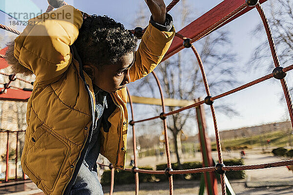 Junge spielt inmitten eines Klettergerüsts auf einem Spielplatz