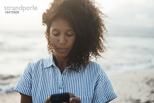 Frau benutzt Mobiltelefon am Strand