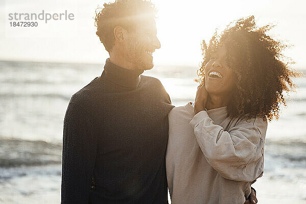 Fröhliches Paar genießt den Sonnenuntergang am Strand