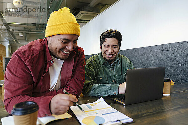 Happy freelancers discussing over chart on table in cafe