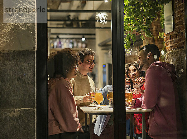 Freunde genießen Bier am Tisch im Restaurant  gesehen durch Glas