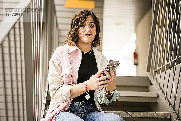 Frau mit Smartphone sitzt auf Treppe