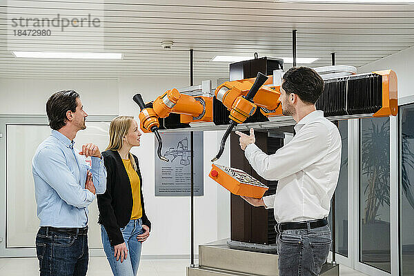 Techniker bedient Roboter in der Nähe von Kollegen in der Fabrik