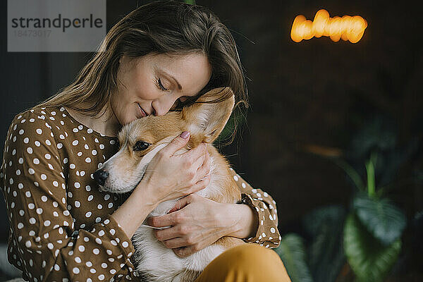Mature woman embracing pet dog at home