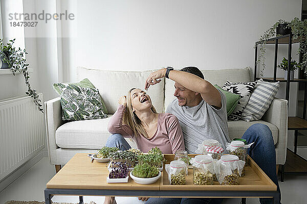 Glückliches Paar  das zu Hause selbst angebaute Kräuter isst