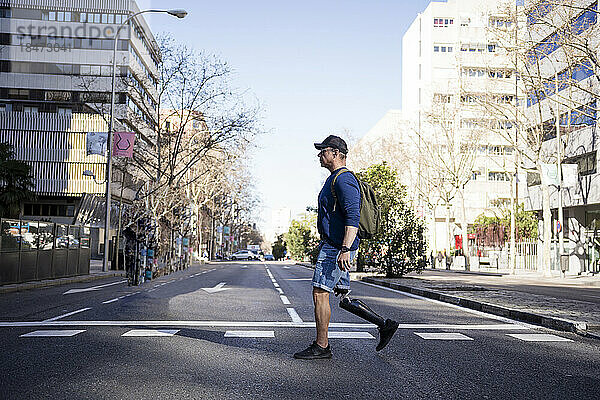 Reifer Mann mit Beinprothese überquert Straße in der Stadt