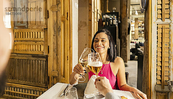 Glückliche Frau stößt mit ihrem Freund im Restaurant auf Weinglas zu