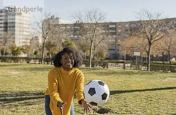 Verspielte Frau fängt Ball im Park