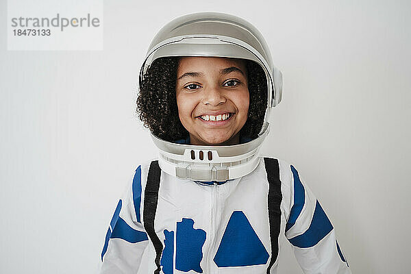Happy girl wearing astronaut's costume in front of white wall