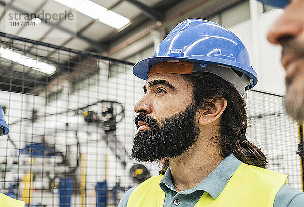 Nachdenklicher Ingenieur mit Bart in der Fabrik