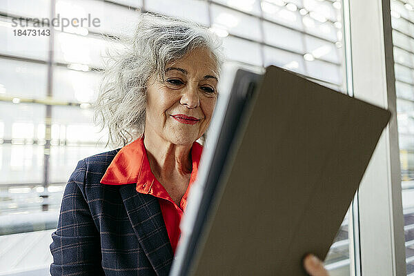 Lächelnde reife Geschäftsfrau mit grauen Haaren  die einen Tablet-PC verwendet