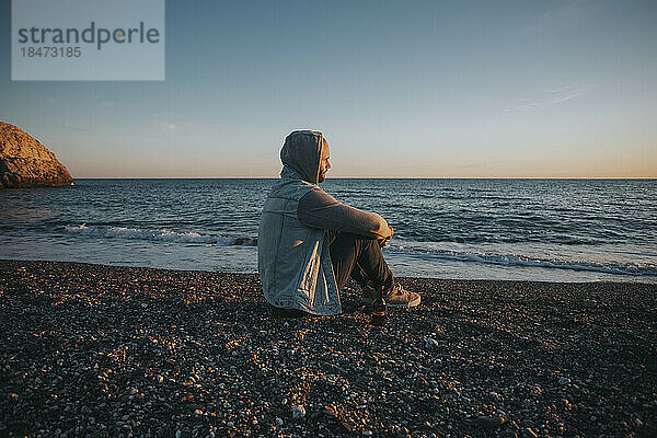 Nachdenklicher Mann sitzt an der Küste am Strand