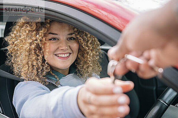 Glückliche Frau  die dem persönlichen Parkservice Autoschlüssel übergibt