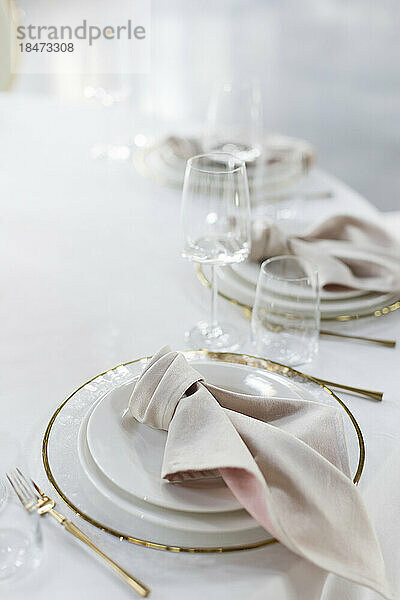 Teller  Servietten und leere Gläser auf elegant gedecktem Tisch