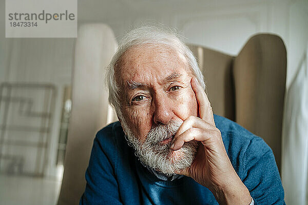 Nachdenklicher älterer Mann mit grauen Haaren  der zu Hause sitzt