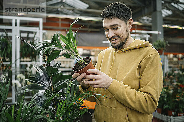 Glücklicher Mann kauft Pflanze im Gartencenter