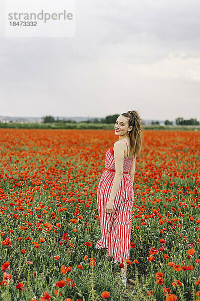 Happy young woman walking at poppy field