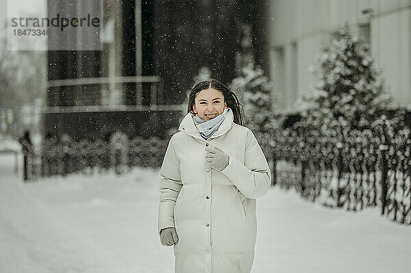 Glückliche Frau in warmer Kleidung  die im Winter spaziert