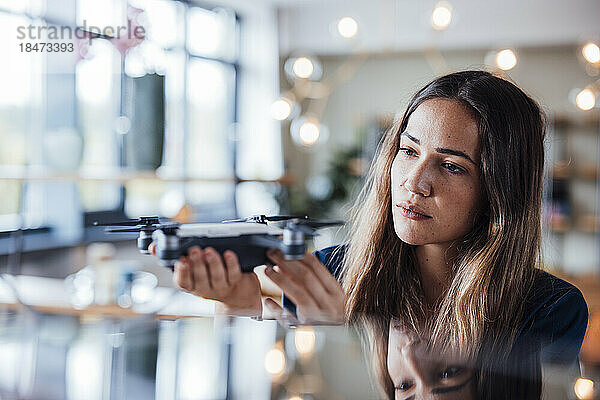 Junge Geschäftsfrau untersucht Drohne im Büro