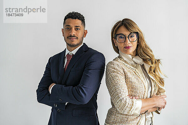 Confident mature businesswoman standing with colleague against white background