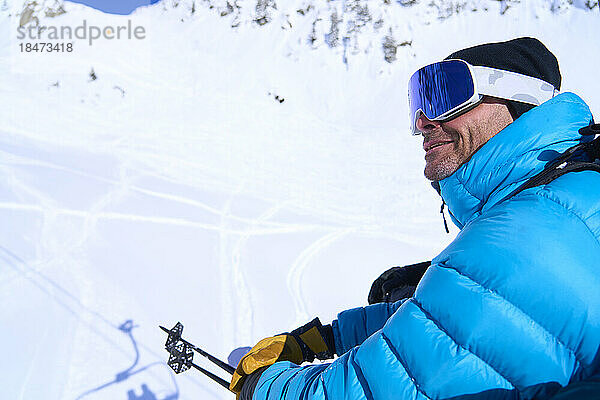 Lächelnder reifer Mann mit Skibrille auf dem Berg