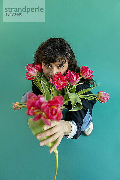 Young woman holding tulips standing on green background