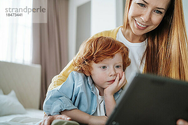 Sohn schaut mit Mutter zu Hause Tablet-PC vorbei