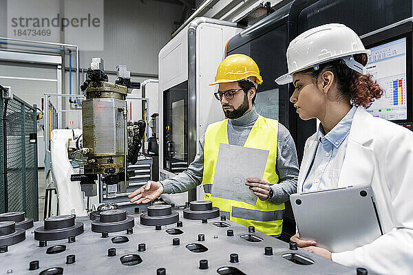 Ingenieur und Kollege untersuchen Maschinenteile in der Fabrik