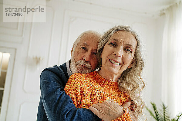 Liebevolles Seniorenpaar umarmt sich zu Hause