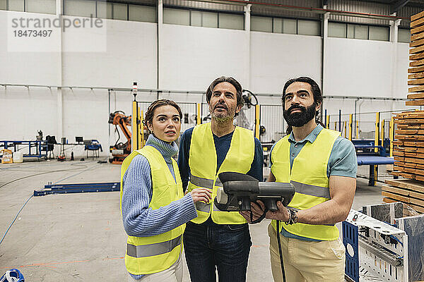 Ingenieure halten Bedienfeld in der Robotikfabrik in der Hand und schauen nach oben