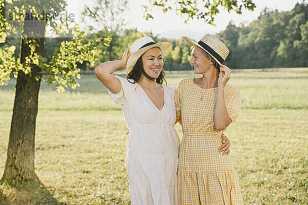 Glückliche Frauen mit Hüten stehen im Park
