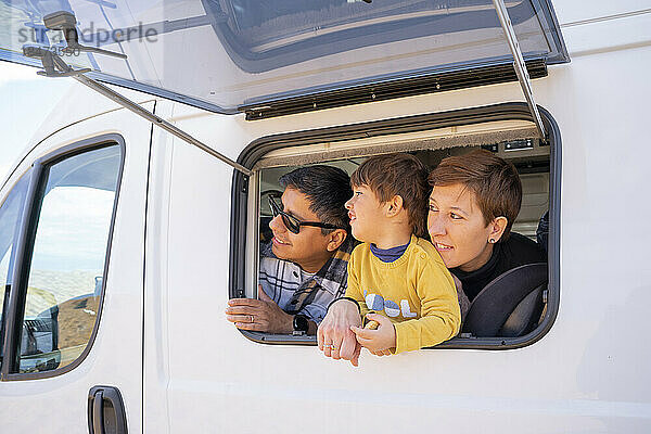 Eltern mit Sohn schauen durch das Fenster eines Wohnmobils