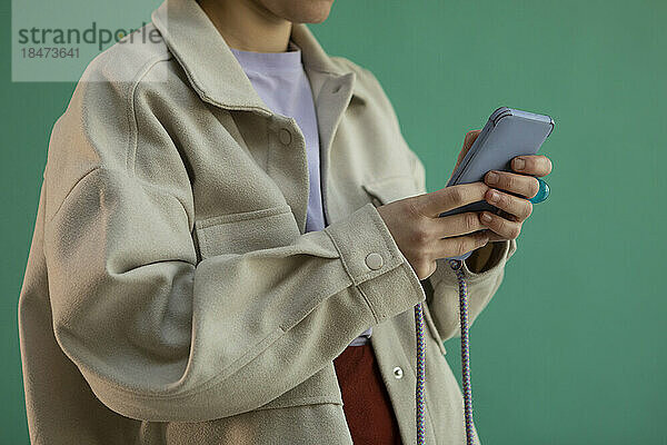 Frau benutzt Smartphone vor grünem Hintergrund