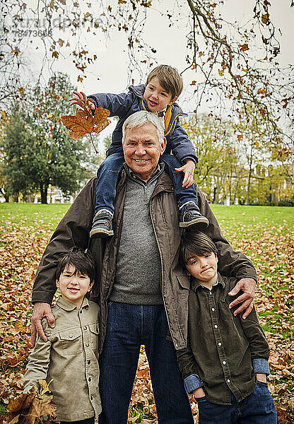 Lächelnder älterer Mann steht mit Enkeln im Park