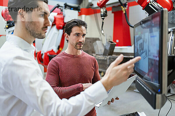 Ingenieure arbeiten am Computerbildschirm in der Roboterfabrik zusammen