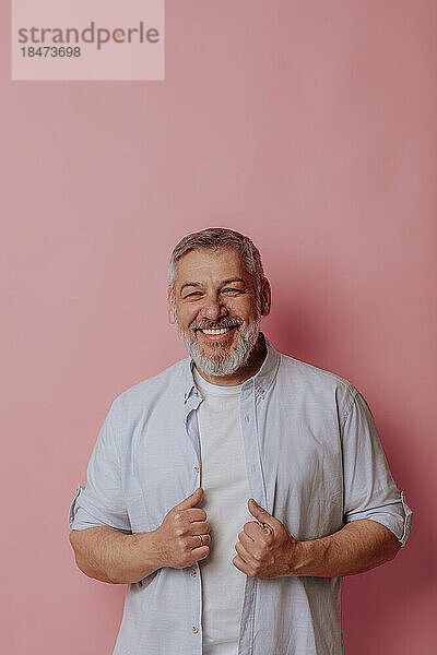 Happy mature man against pink background