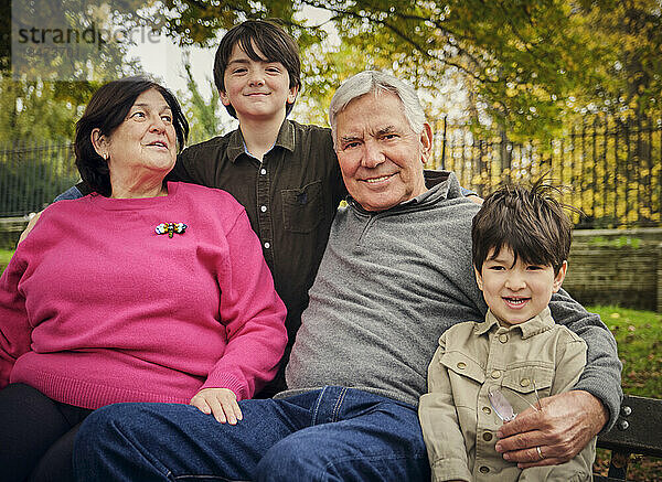 Lächelnde Enkel sitzen mit Großeltern im Park