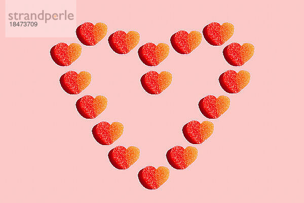 Herzförmige Süßigkeiten flach vor rotem Hintergrund gelegt