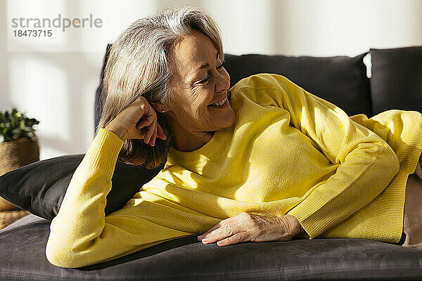 Happy mature woman relaxing on sofa at home