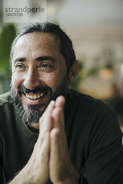 Happy mature man with beard in cafe