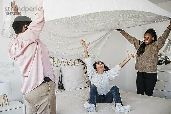 Mädchen amüsiert sich mit Mutter und Großmutter im heimischen Schlafzimmer
