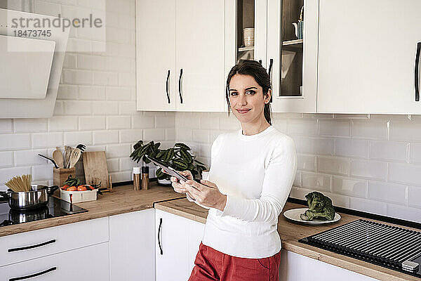 Lächelnde Frau mit Tablet-PC in der Küche