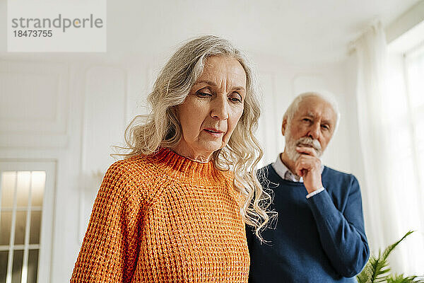 Ältere Frau mit nachdenklichem Mann zu Hause